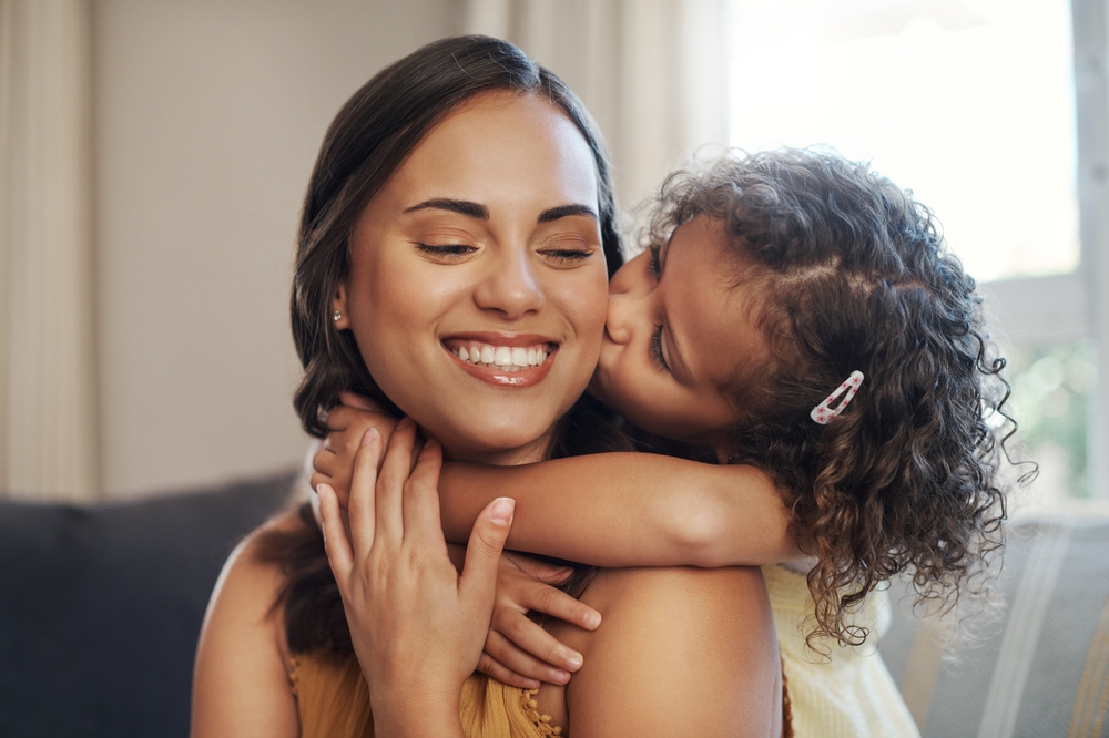 A smiling woman hugging a young girl affectionately